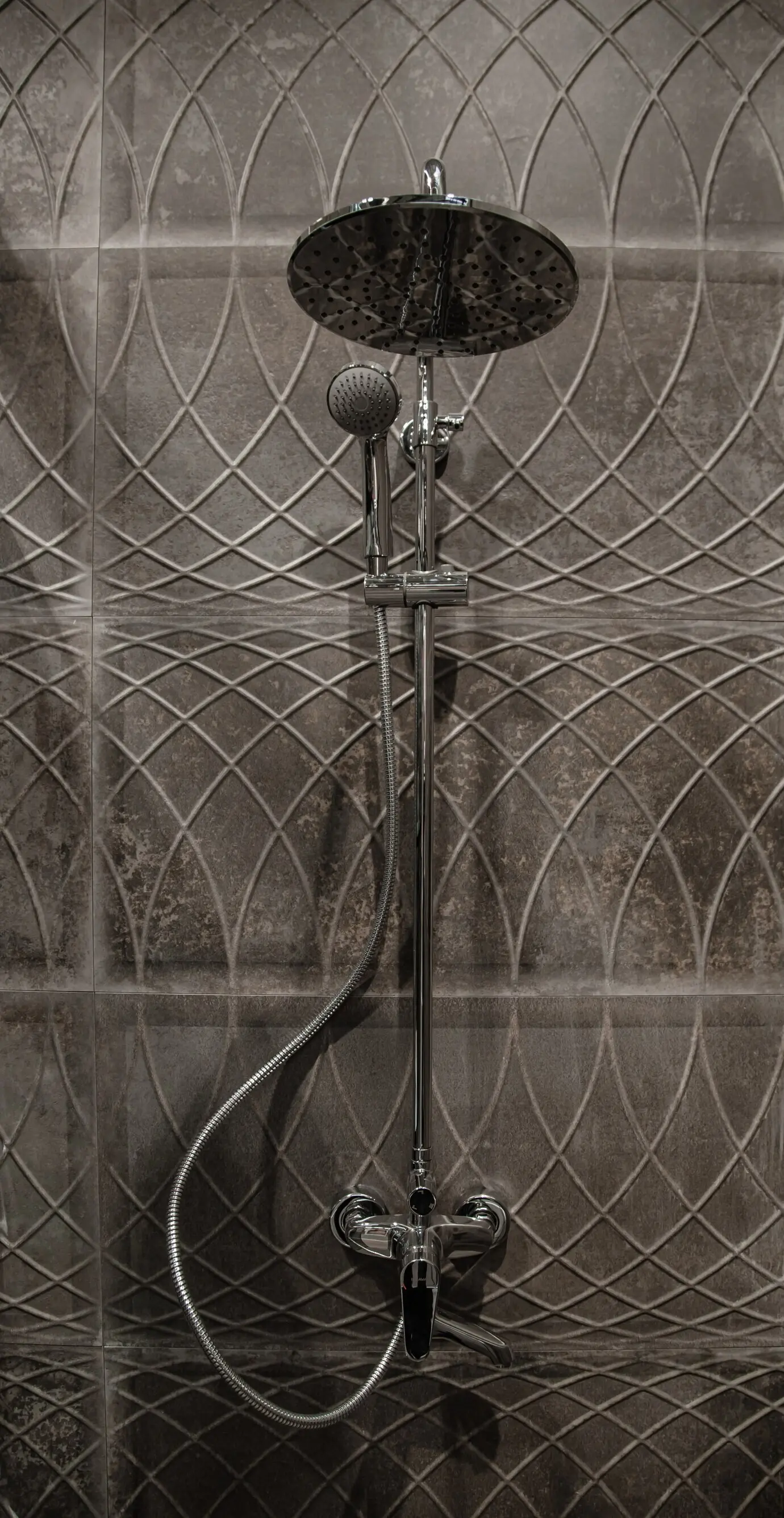 A modern bathroom interior featuring a shower, set against a wall with beautiful tiles.